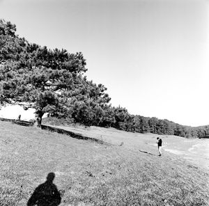 People walking on field against clear sky