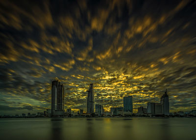 Scenic view of river by buildings against cloudy sky