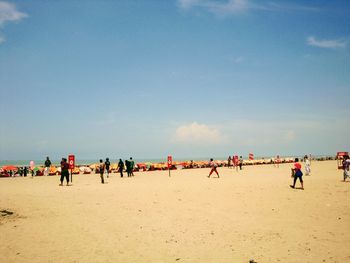 People at beach against sky during sunny day