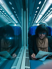 Woman sitting in illuminated subway train