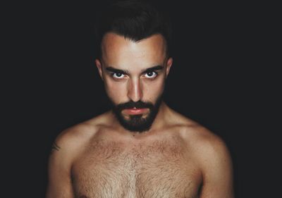 Portrait of shirtless man against black background