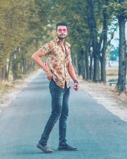 Full length portrait of young man standing on road