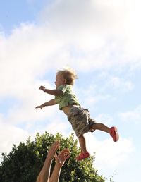 Low angle view of boy jumping against sky