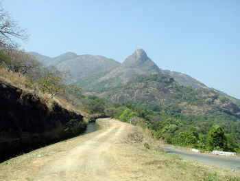 Scenic view of road amidst mountains against clear sky