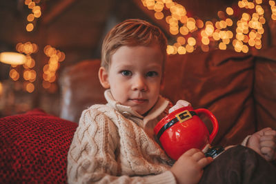 Portrait candid happy kid in knit beige sweater hold xmas mug with marshmallows and candy cane