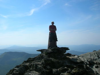 Male hiker standing on mountain against blue sky