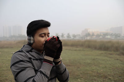 Young man looking away on field during winter