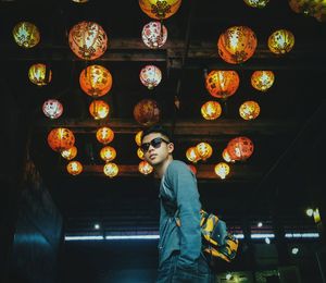 Low angle view of woman standing against illuminated ceiling
