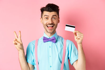 Portrait of smiling man standing against pink background