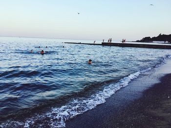 People on beach against clear sky