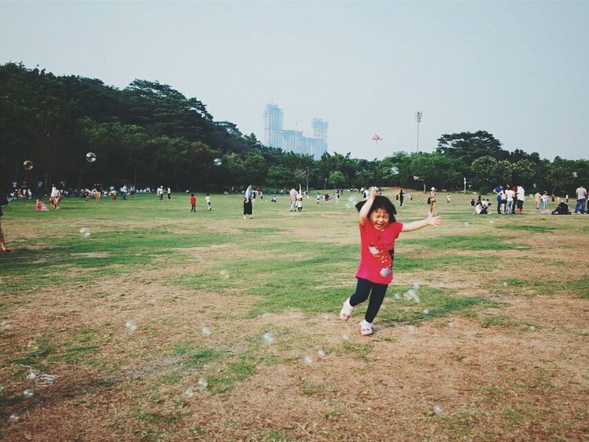 leisure activity, lifestyles, grass, large group of people, person, tree, men, full length, park - man made space, building exterior, clear sky, walking, casual clothing, field, architecture, enjoyment, built structure, city, tourist