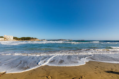 Scenic view of beach against clear blue sky