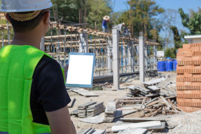 Rear view of engineer holding digital tablet at construction site