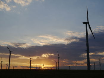 Silhouette windmill on field against sky during sunset