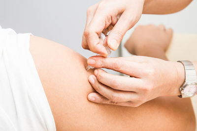 Cropped hand of female doctor vaccinating male patient in clinic