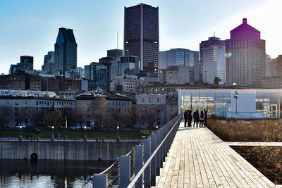 People on footpath by buildings against sky