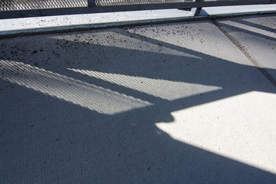 High angle view of shadow of railing on footpath