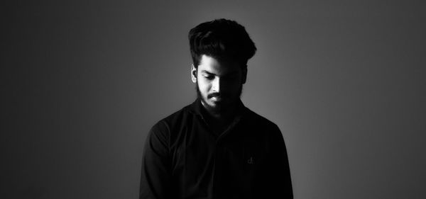 Thoughtful young man standing against gray background