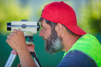 A man works with an optical level to level the landscape.