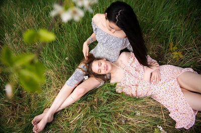 A young girl is lying on her sister's lap with black hair person