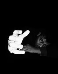 Close-up of young woman with hand on black background