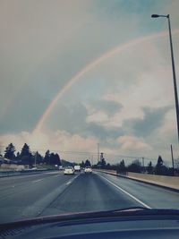 Rainbow over road seen through windshield