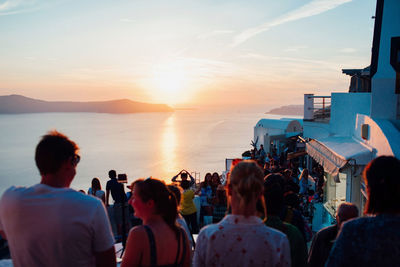 People photographing sea against sky during sunset