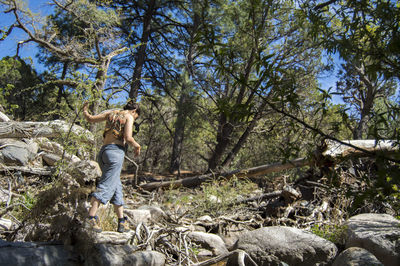 Rear view of woman walking on rocks in forest