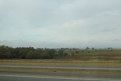 Road by trees against sky