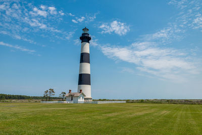 Lighthouse on field against sky