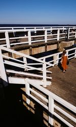 Rear view of man standing by railing against sky