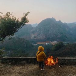 Rear view of man with arms outstretched against mountain