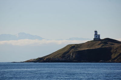 Lighthouse by sea against sky