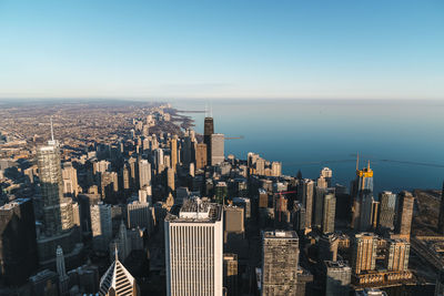 Aerial view of modern buildings by lake against sky