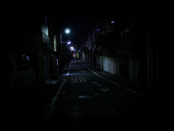 Surface level of empty road along buildings at night