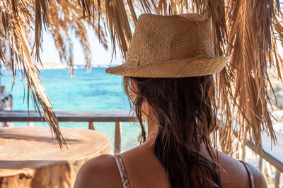 Back view of woman in hat watching the sea.