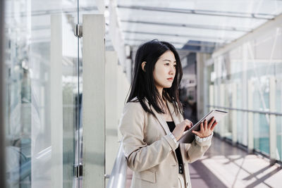 Portrait of young woman standing against building