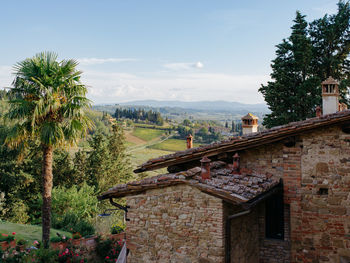 House and palm trees on landscape against sky