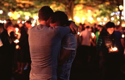 Rear view of man hugging friend in park