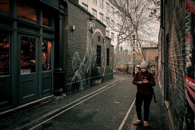 Woman standing on street amidst buildings in city