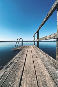 Pier over sea against clear blue sky