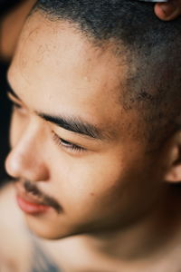 Close-up of man with shaved head looking away