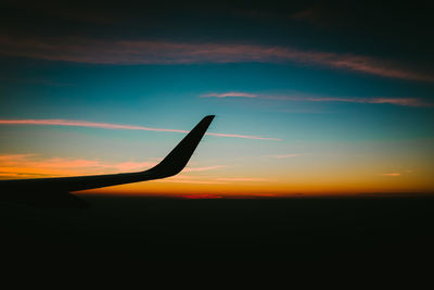 Silhouette airplane against sky during sunset