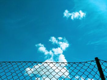 Low angle view of chainlink fence against blue sky