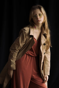 Portrait of young woman standing against curtain