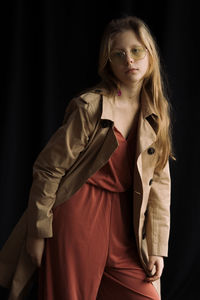 Portrait of young woman standing against curtain
