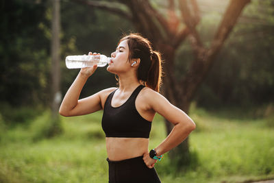 Portrait of young woman drinking water from bottle