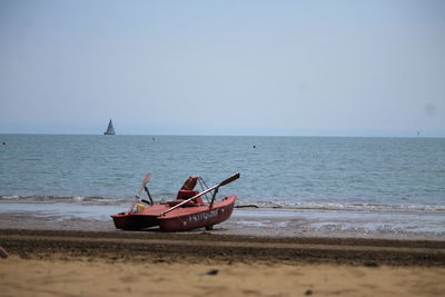 Boat moored on beach against clear sky