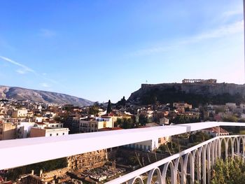 Bridge over river by buildings in city against sky