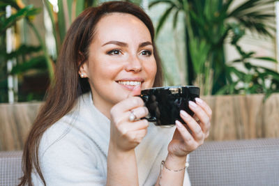 Portrait of a smiling young woman holding drink